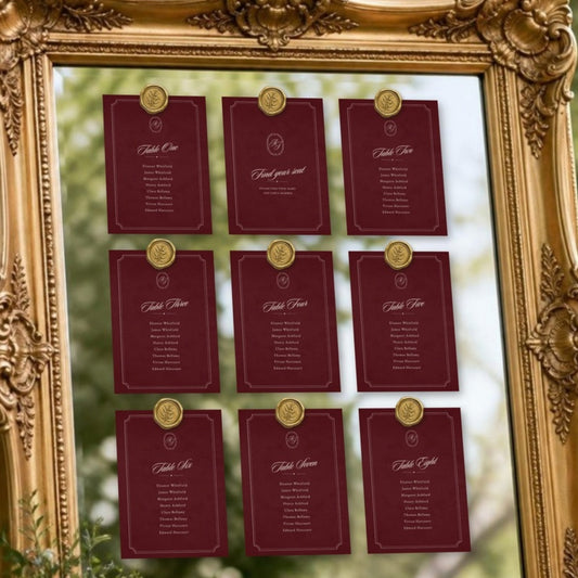 Old Money Classic burgundy seating chart cards with gold seals on a gilded mirror