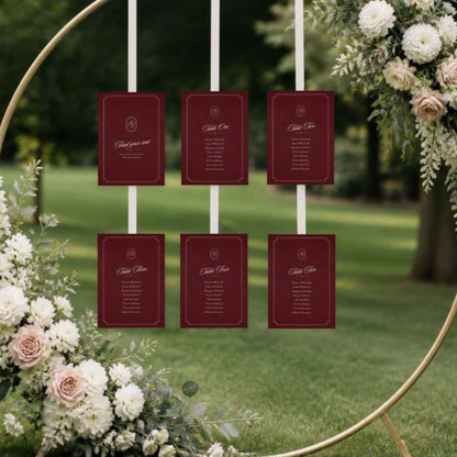 Seating chart cards hung on ribbons from a floral hoop arch on a lawn