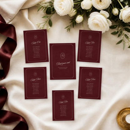 Burgundy find your seat and table cards laid flat with white roses
